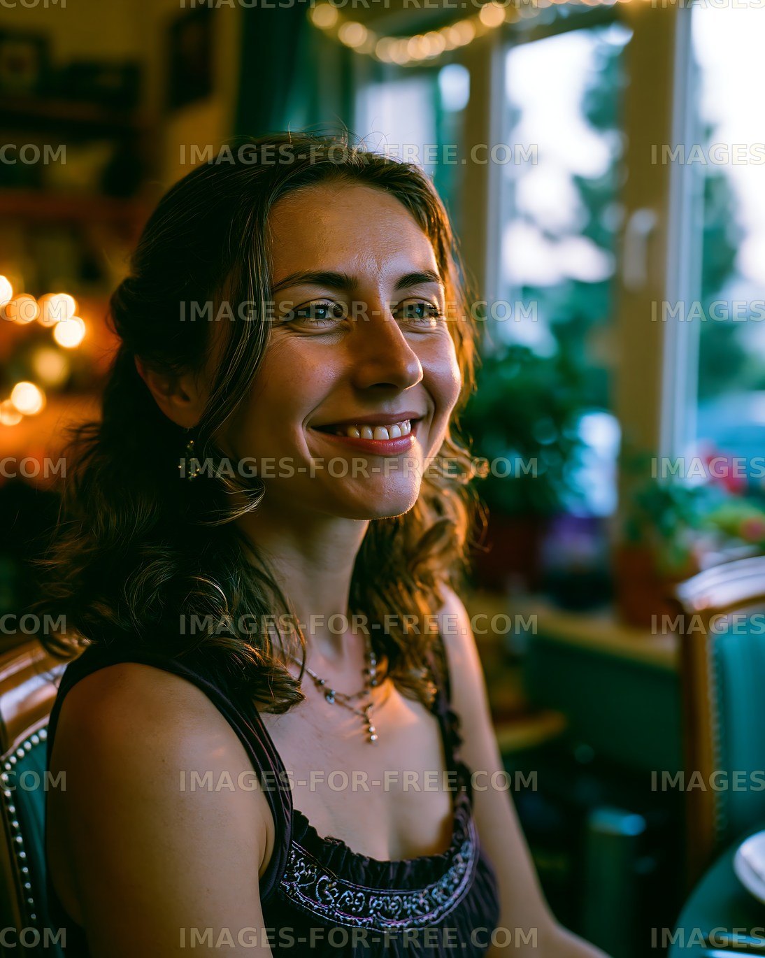 Woman smiling by the window with warm lights in the background