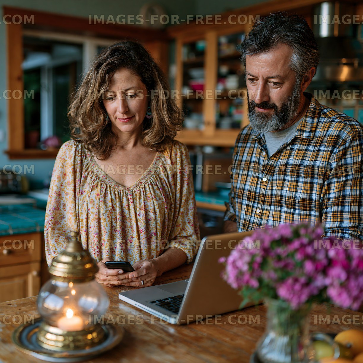 Couple using a laptop and smartphone in a cozy kitchen