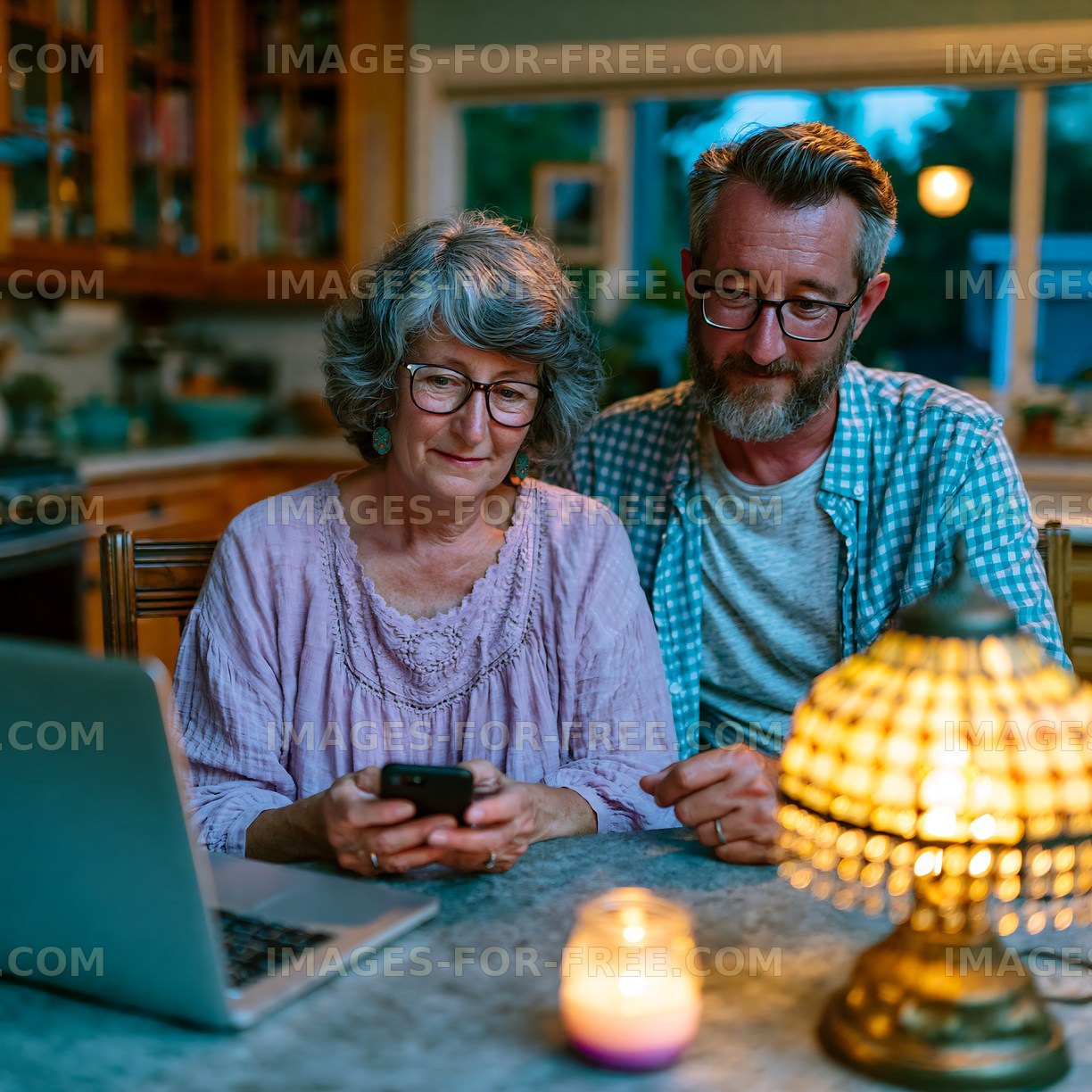 Couple using smartphone and laptop at table in cozy home setting