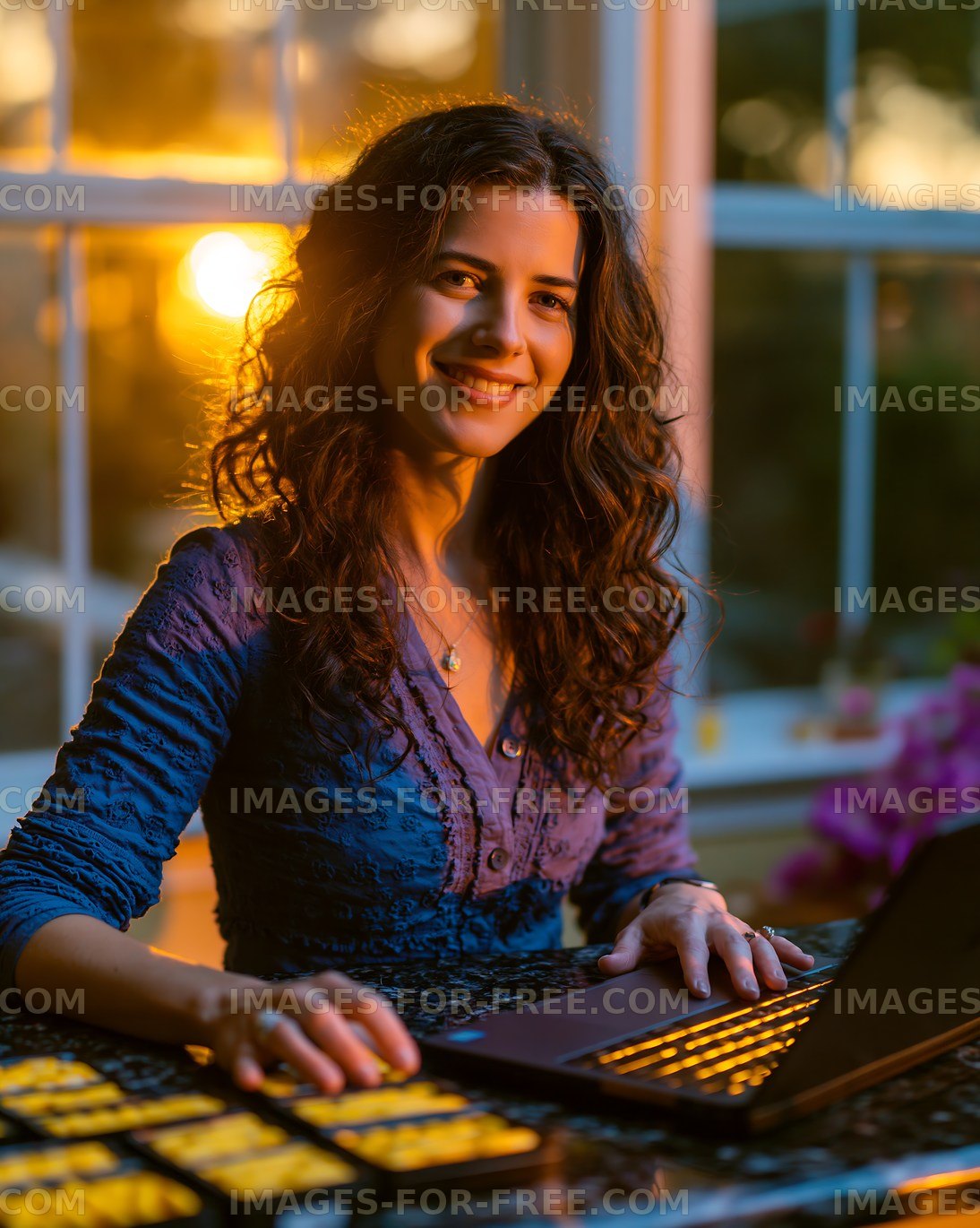 Woman working on laptop during sunset at home