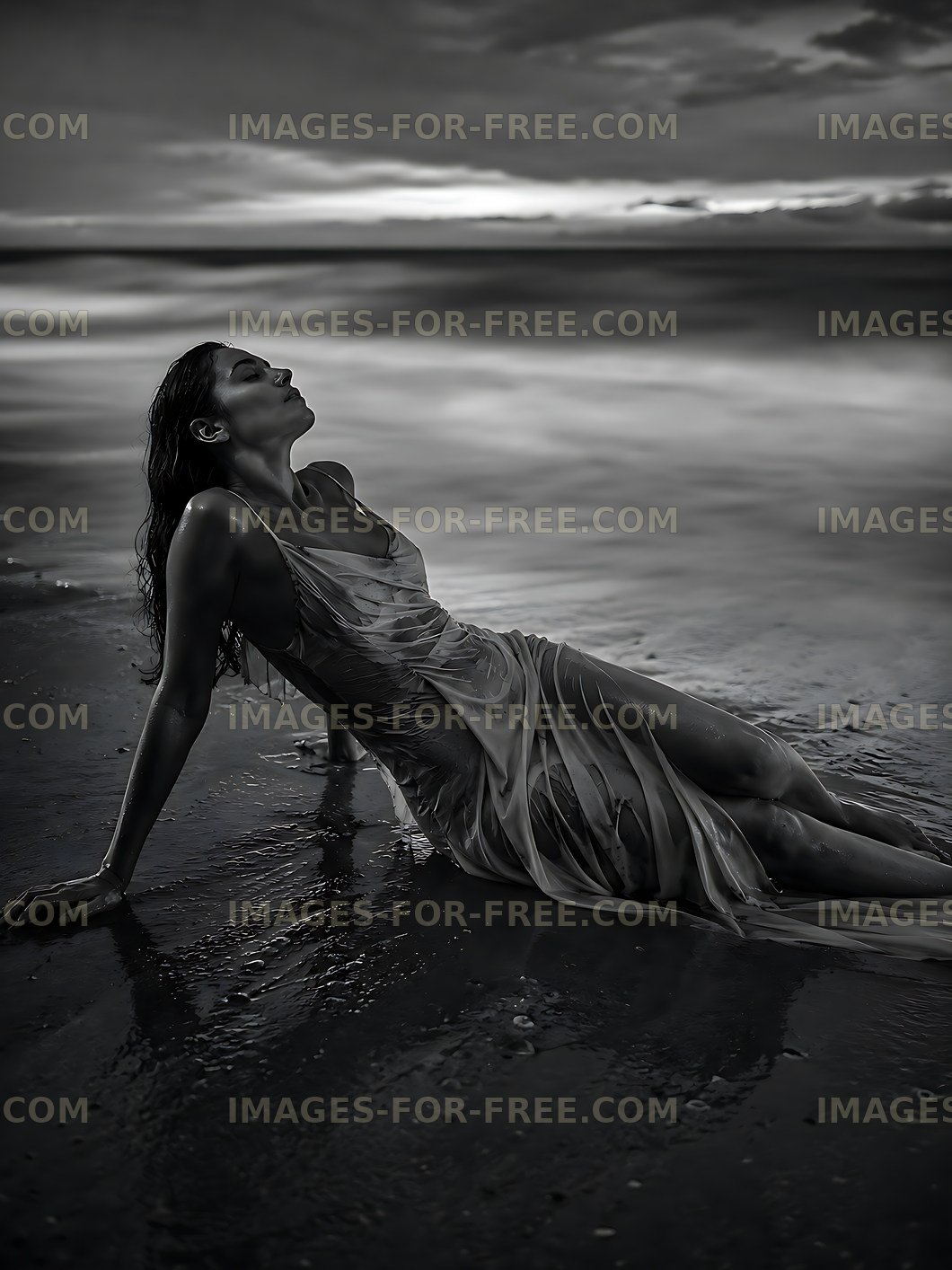 Woman sitting on wet sand by the ocean at sunset