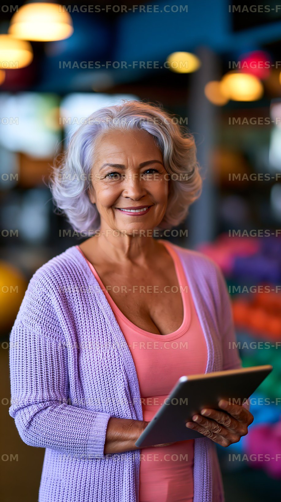 Smiling senior woman holding tablet in colorful background