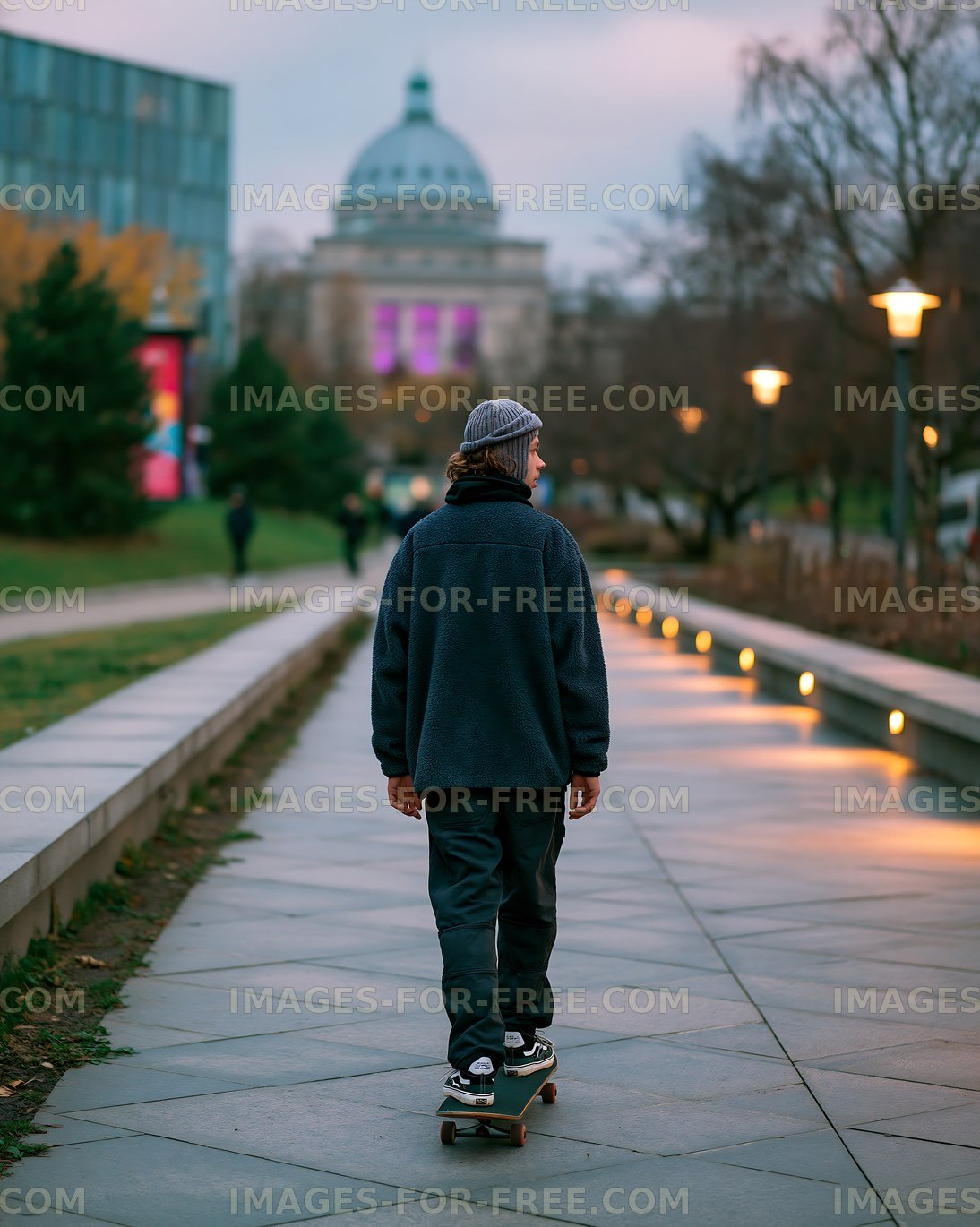 Skater riding along a pathway with city buildings in the background
