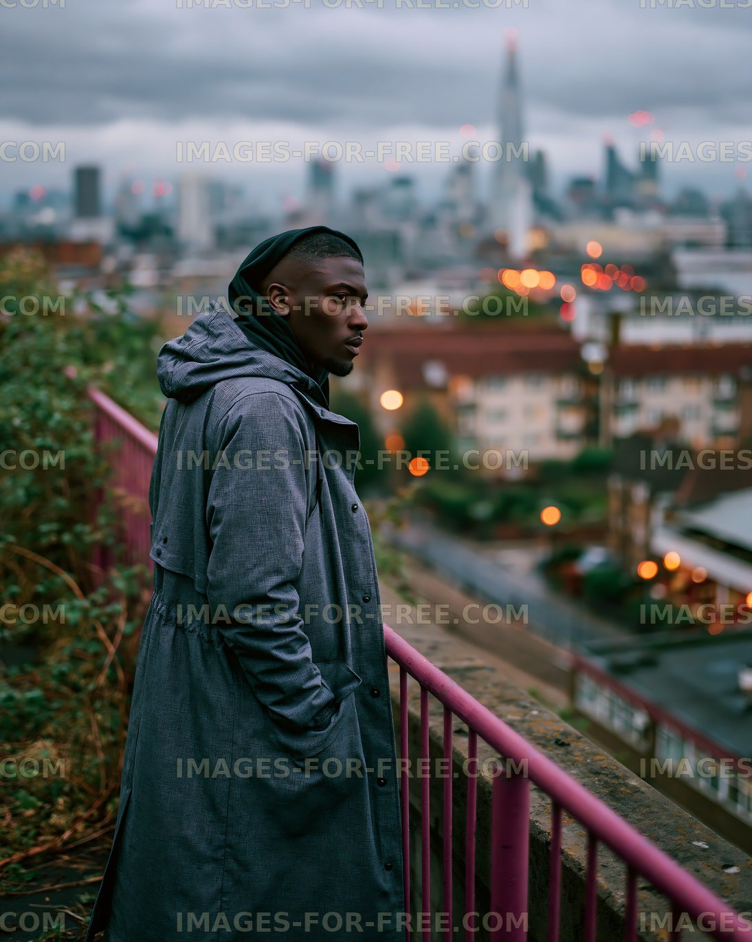 Man in gray coat looking over city skyline at dusk