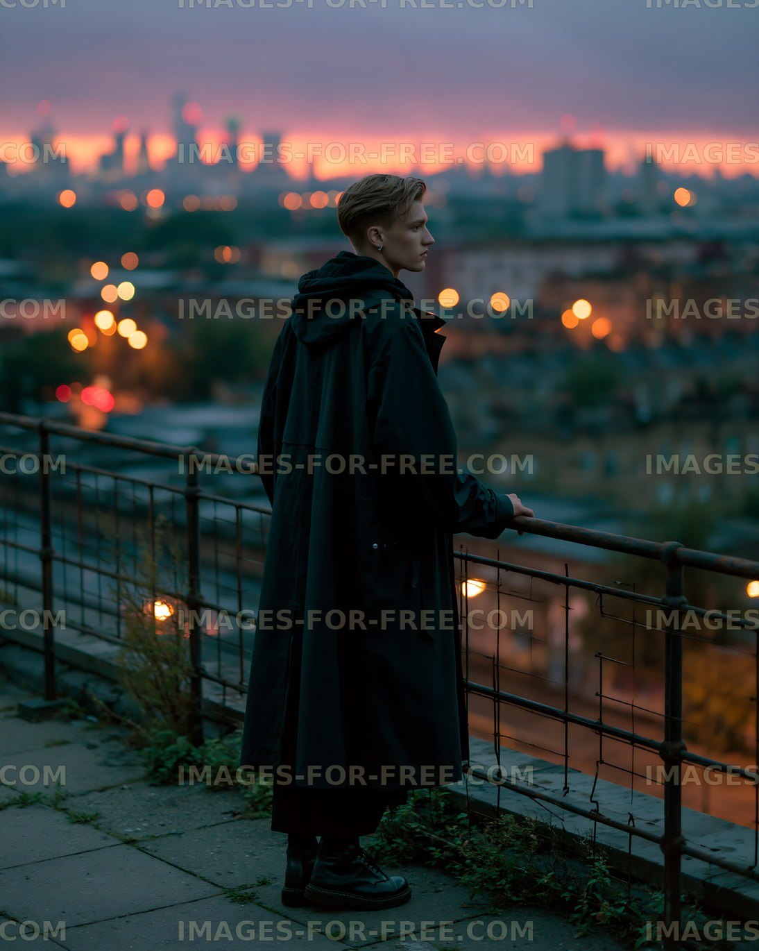Young person standing on rooftop railing during sunset in city