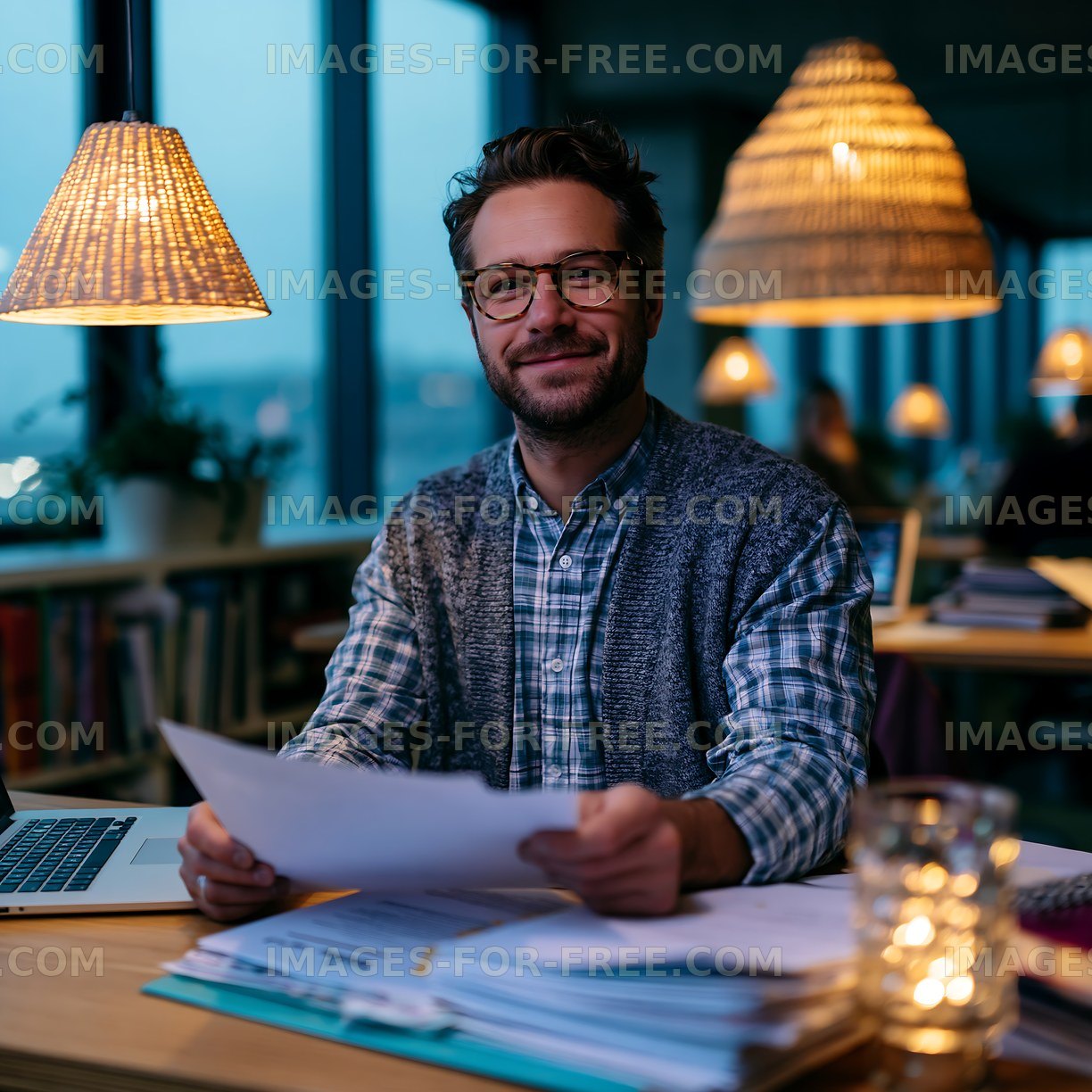 Man working at a desk with papers and a laptop in a cafe
