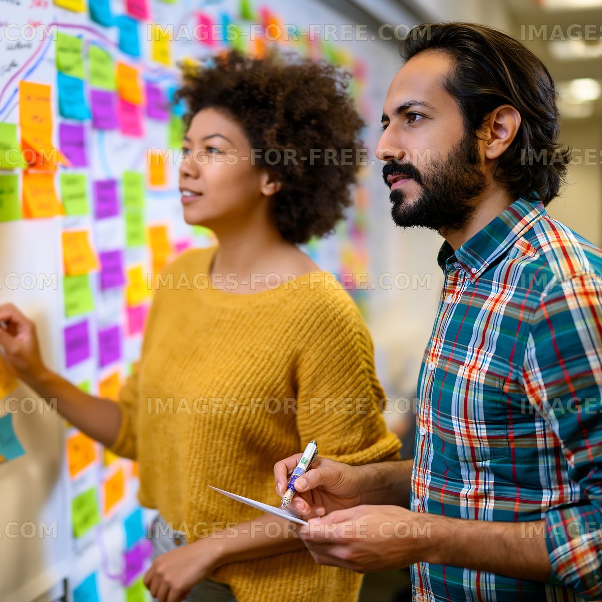 Team members discussing ideas on a wall covered with sticky notes