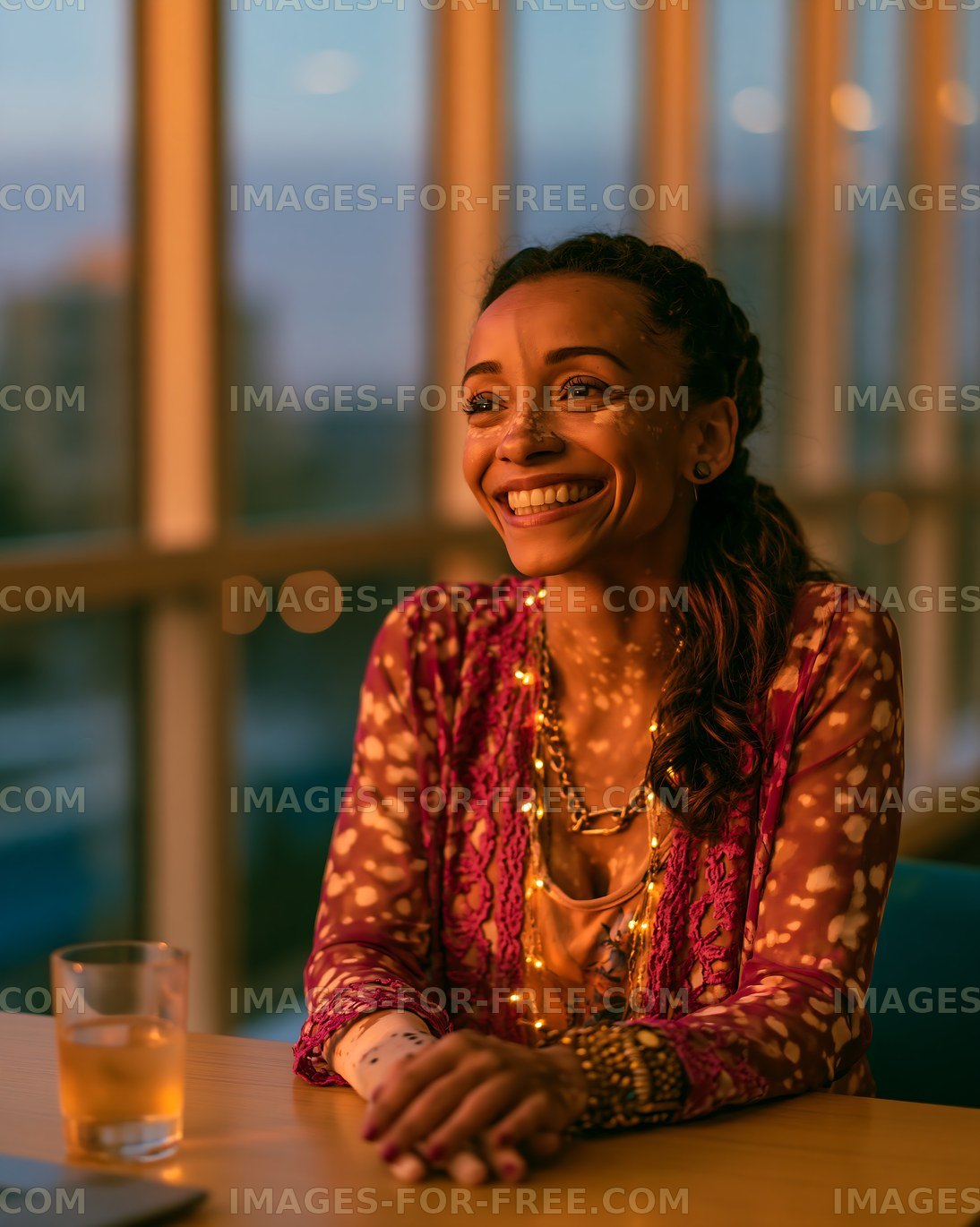 Woman smiling at sunset while sitting at a table in a bright room