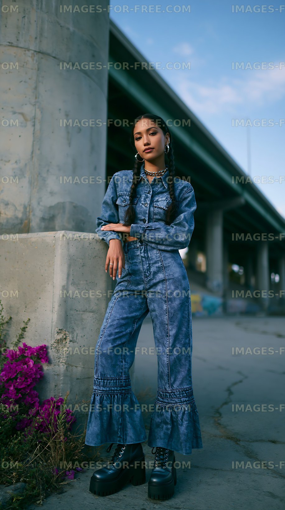 Model poses in denim outfit near concrete structure with flowers