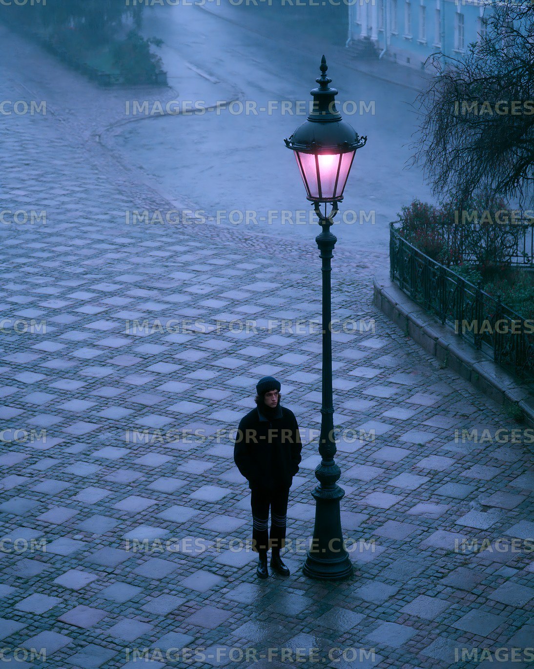 Person standing under a lamp post on a rainy street