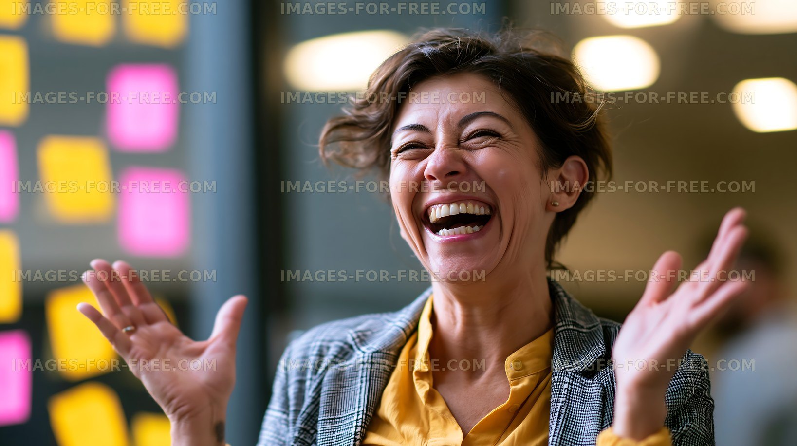 Woman laughing with hands raised in a modern office space