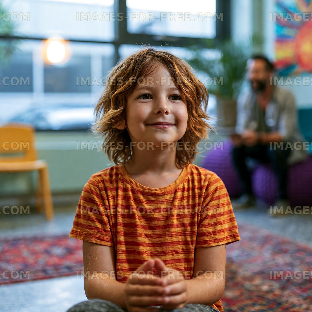 Boy sitting in a colorful room with a smile on his face