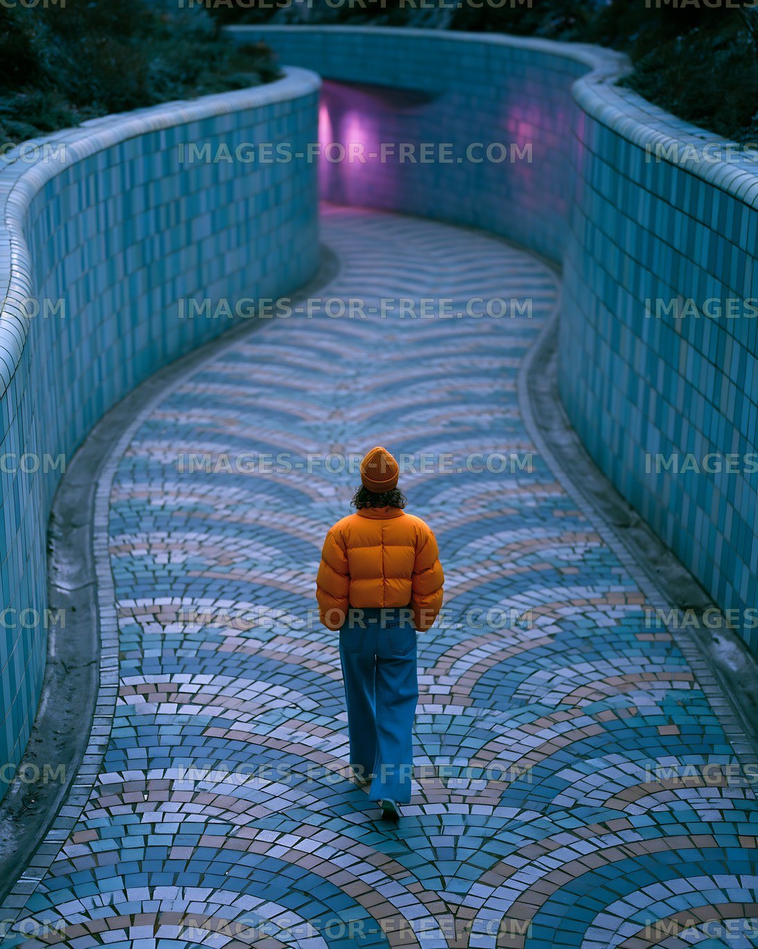 Person walking on a winding path with colorful tiles at night