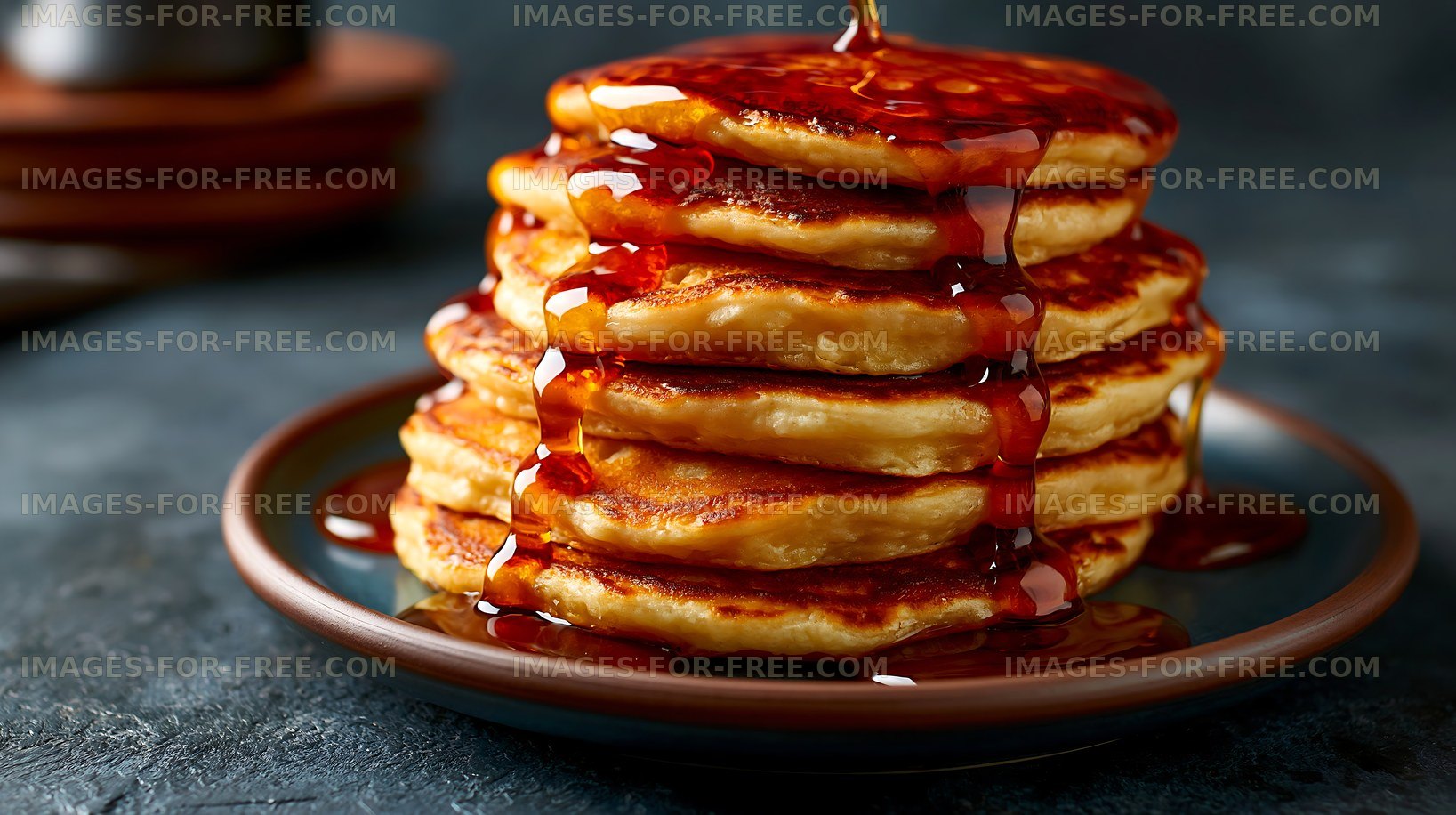 Stack of pancakes with syrup on a dark plate