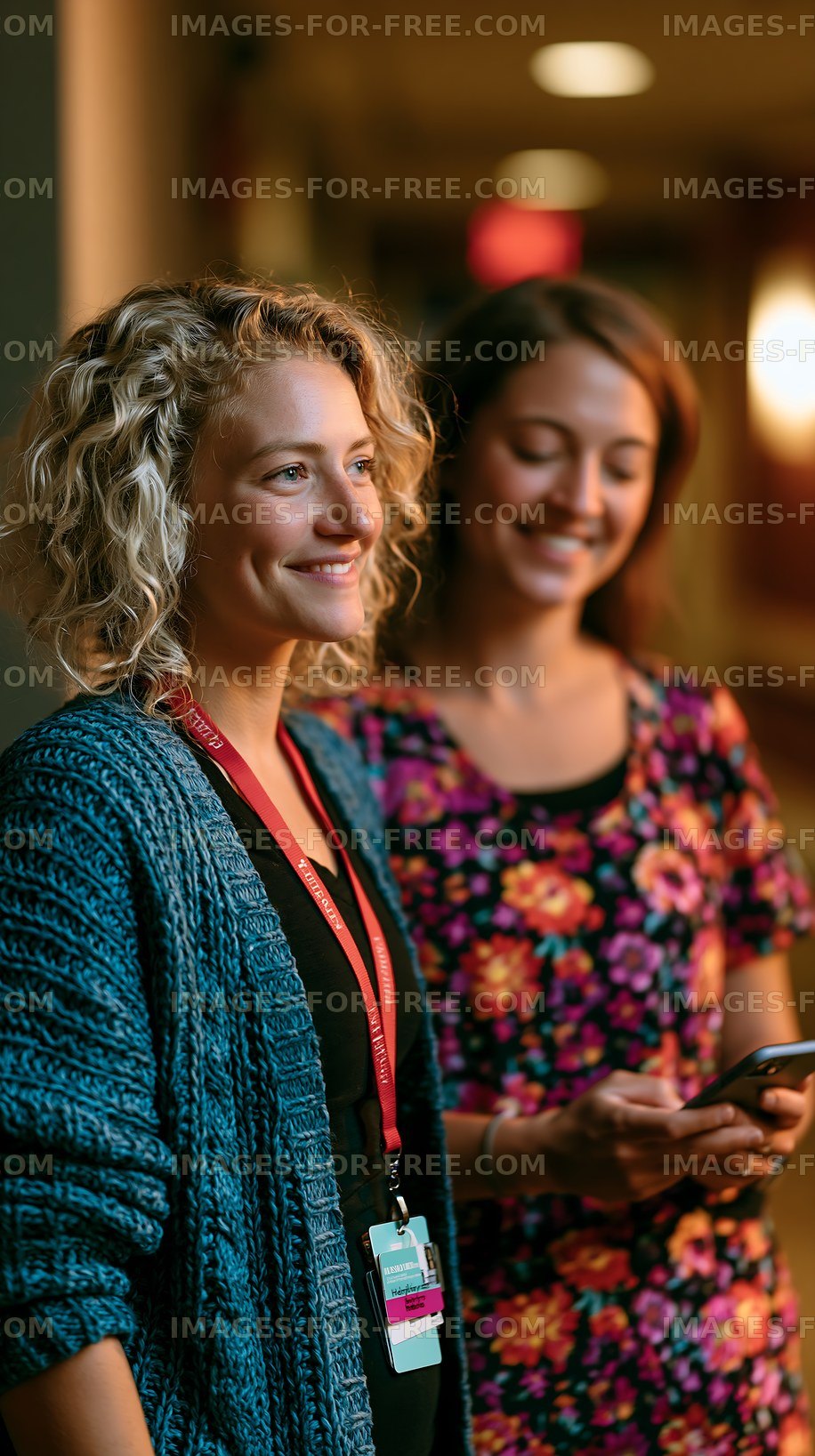 Two women standing in a corridor with smiles on their faces