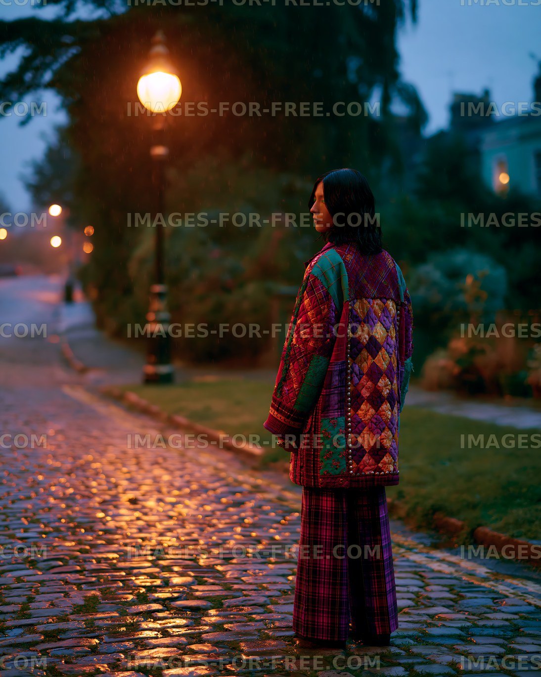 Woman in colorful jacket standing on cobblestone street at dusk