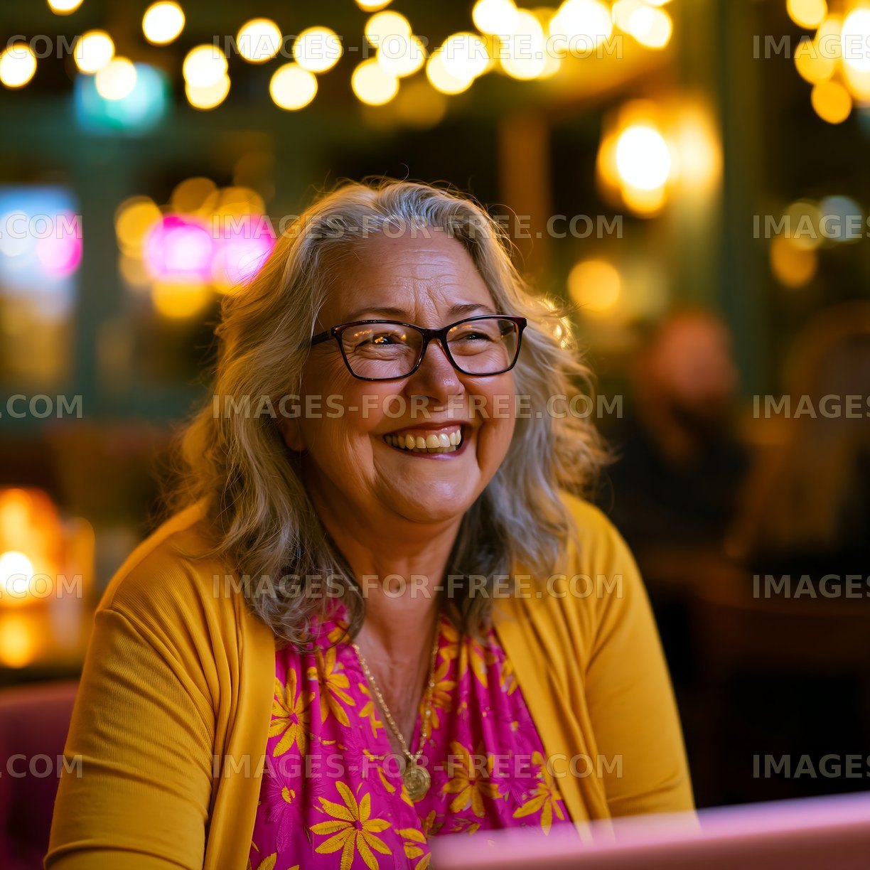 Smiling woman with glasses sitting in a cafe with warm lights