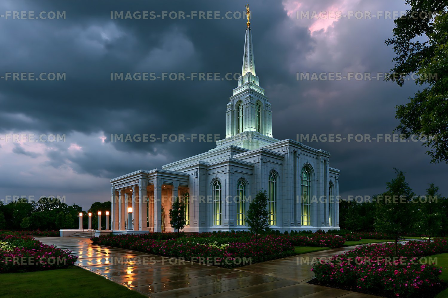 Building with tall spire under dark sky near blooming flowers