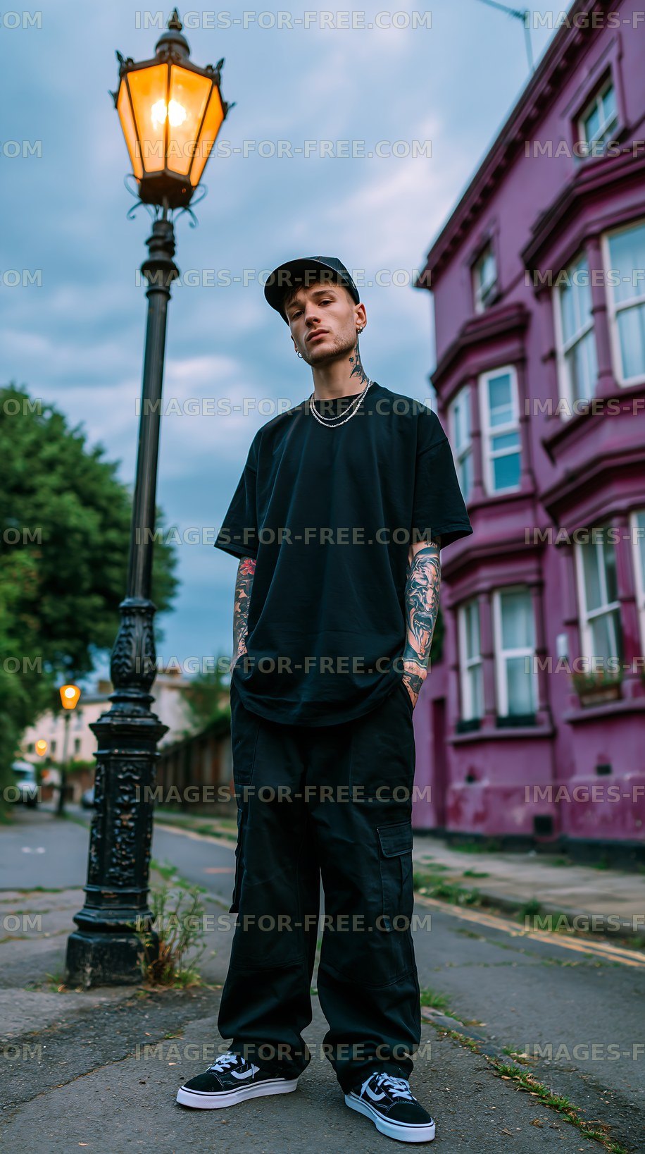 Man standing near lamp post along street with pink building