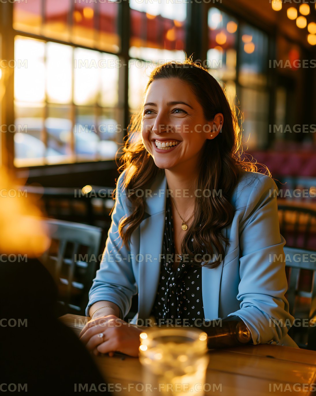 Woman smiles at sunset in a restaurant, enjoying conversation