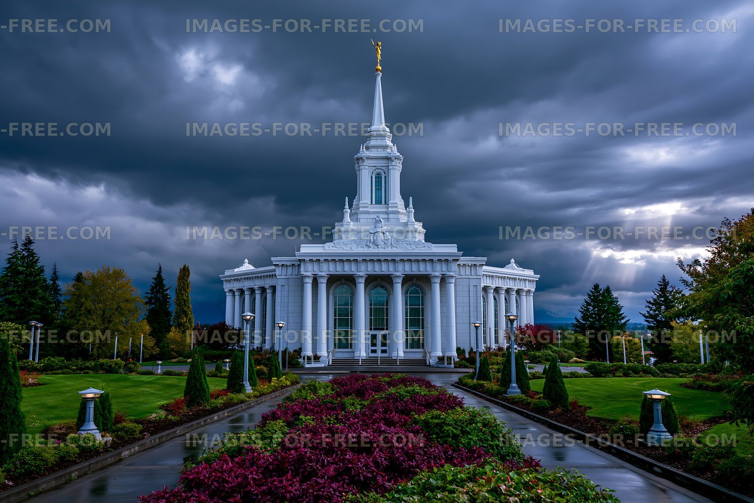Building with a tall spire under dark clouds in a garden