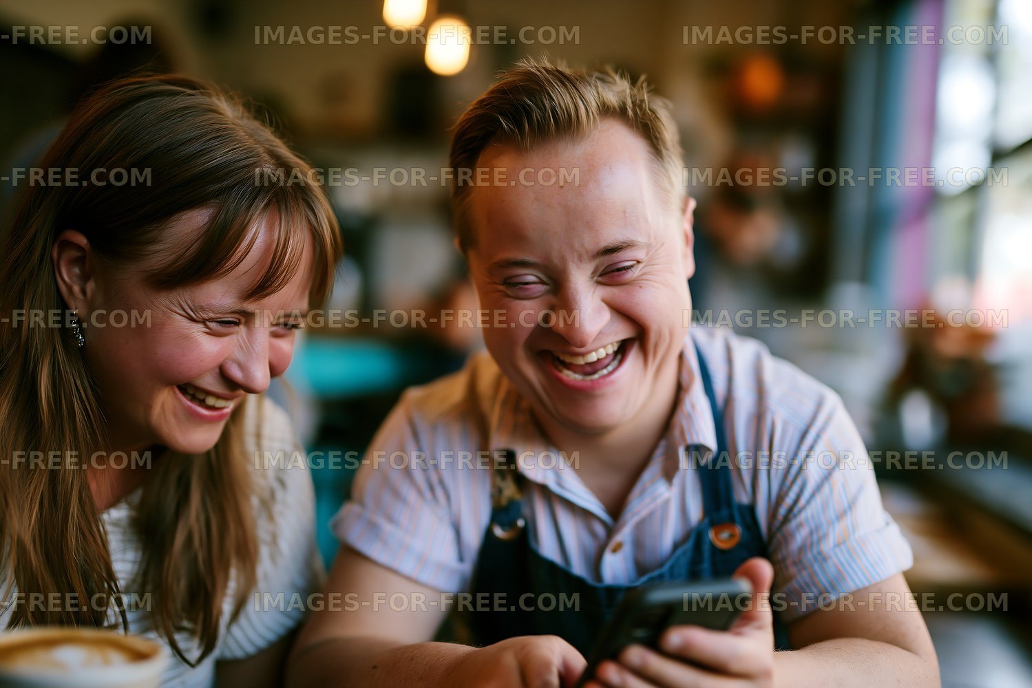 Two people laughing while looking at a phone in a cafe