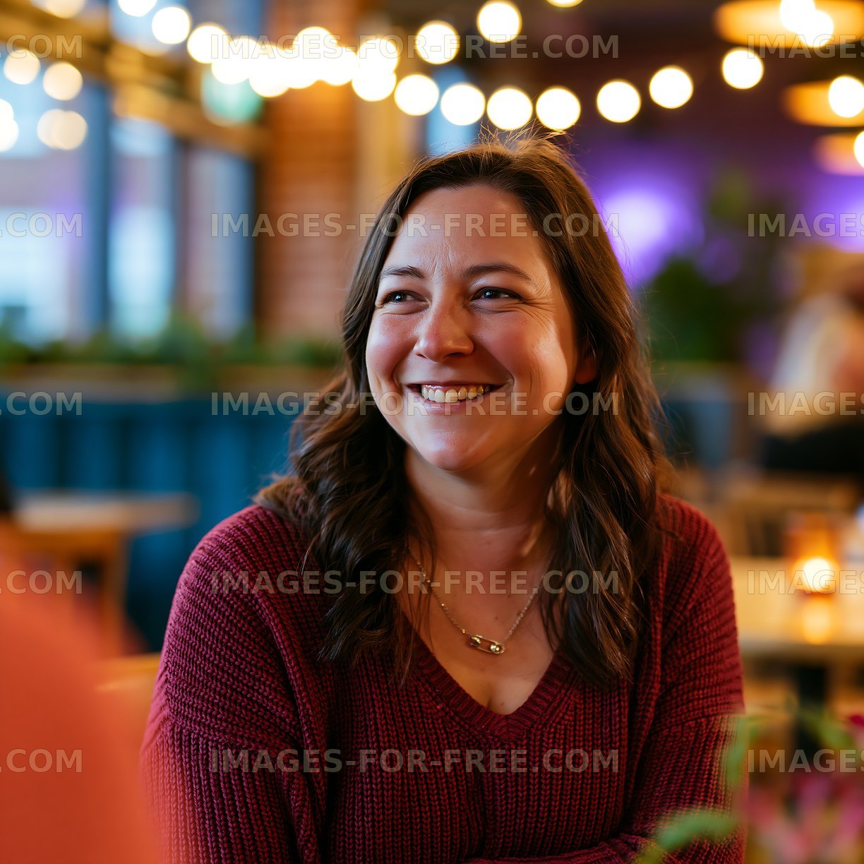 Woman smiles while sitting in a restaurant with warm lighting