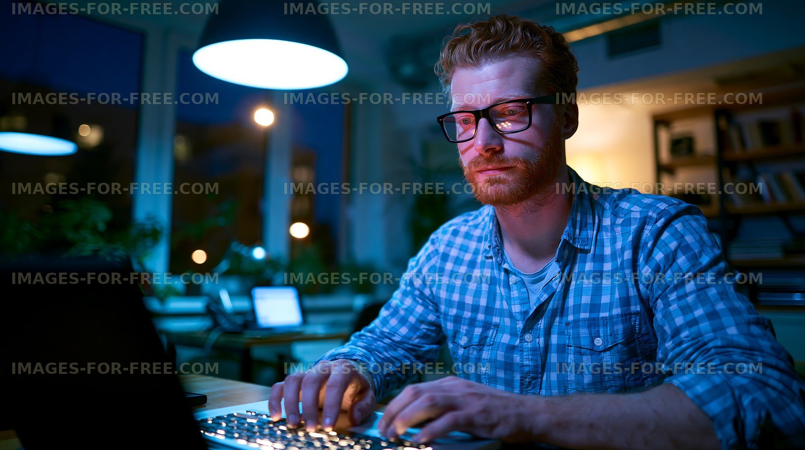 Man working on laptop in dimly lit room at night