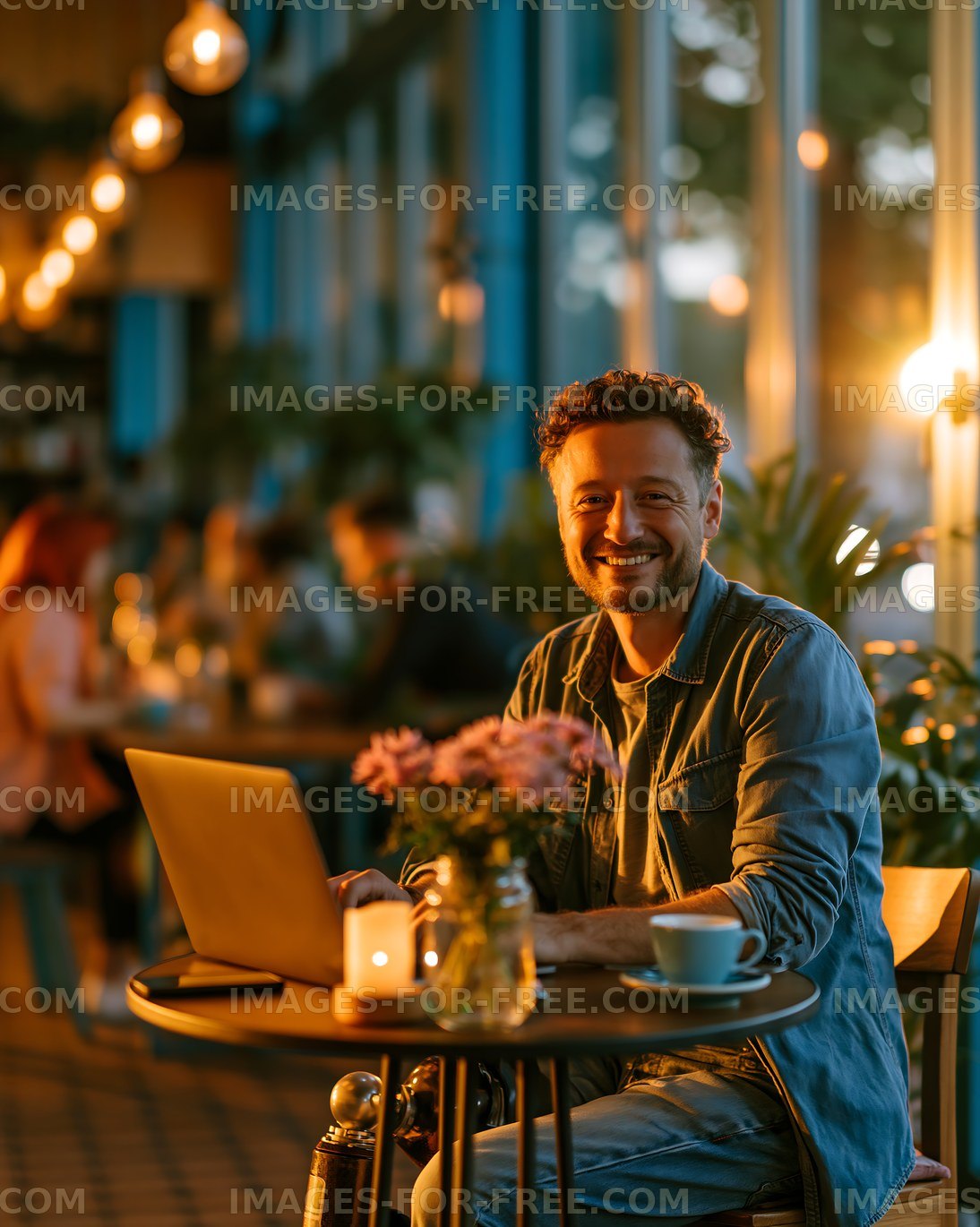 Man working on laptop in cafe during evening with warm lighting