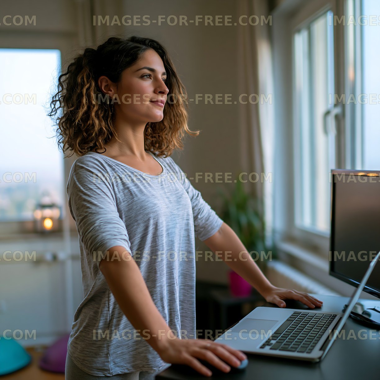 Woman standing at desk while working on laptop in home office