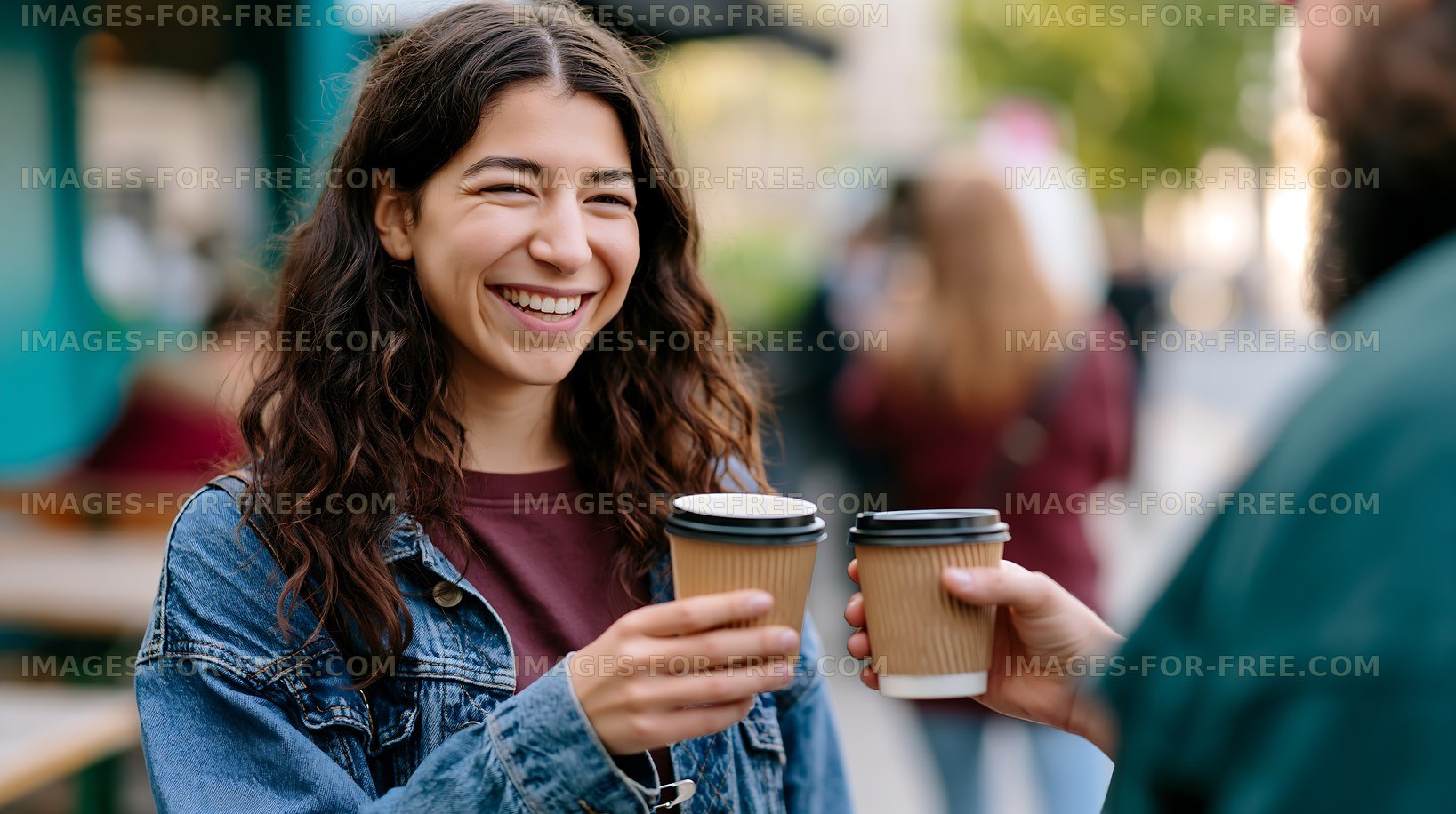 Woman smiling while receiving coffee from a friend outdoors