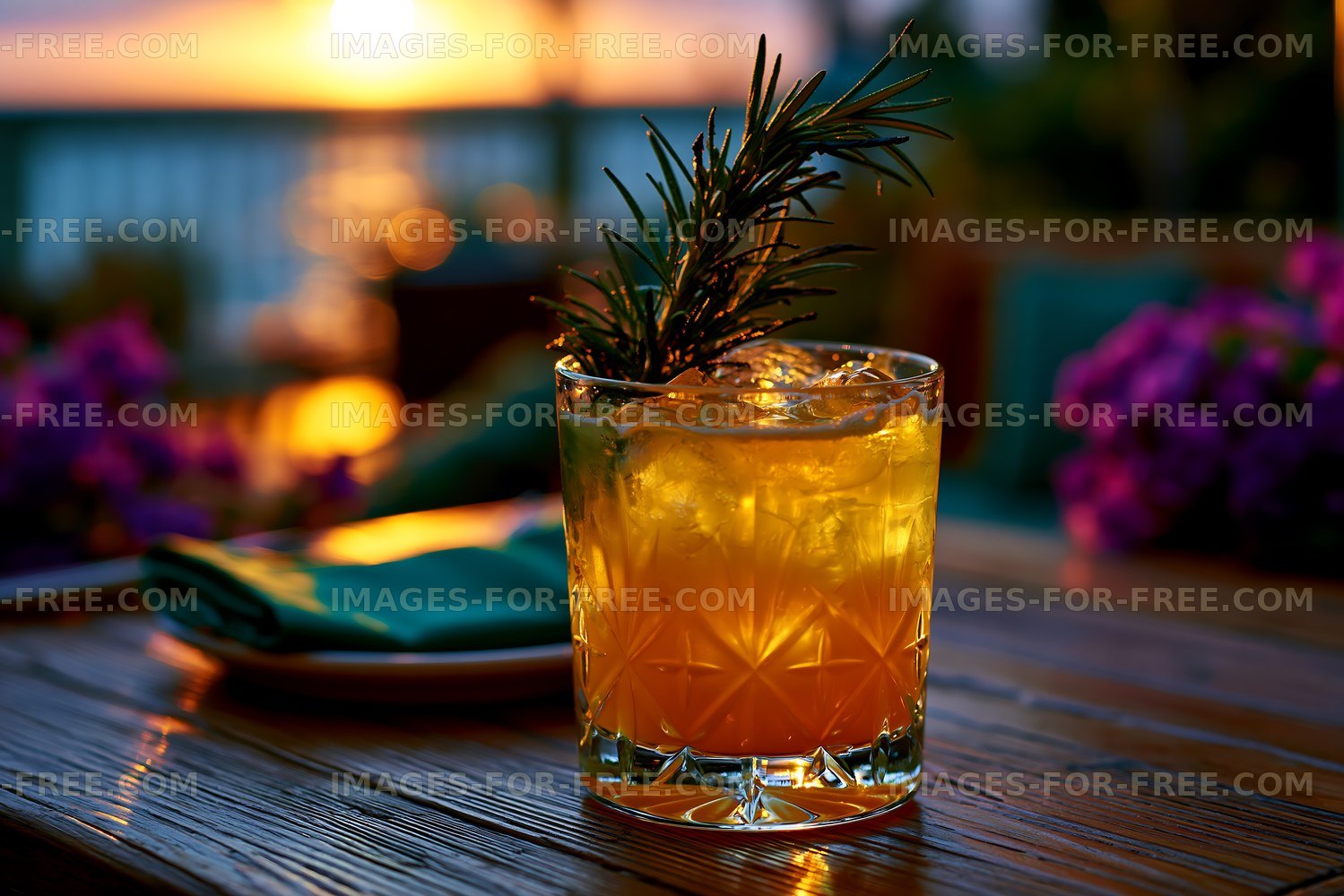 Sunset cocktail with rosemary on wooden table by the sea