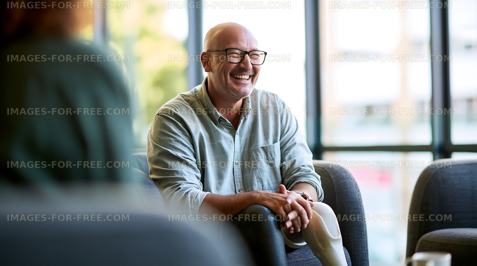 Smiling man sitting indoors while talking to a friend