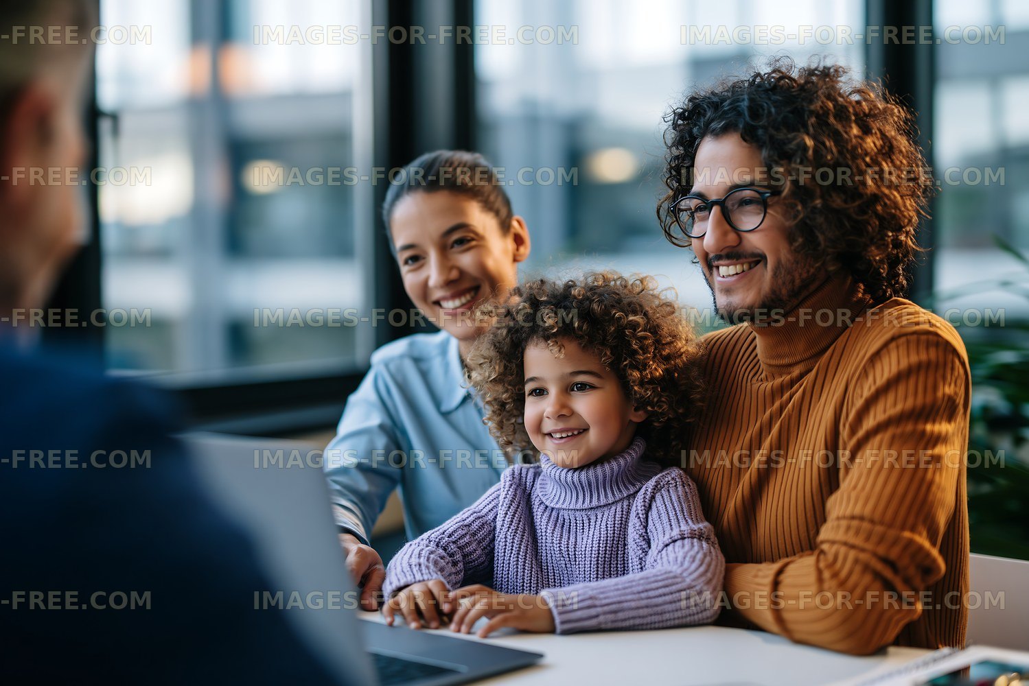 Family working together at a table with a laptop in a bright room