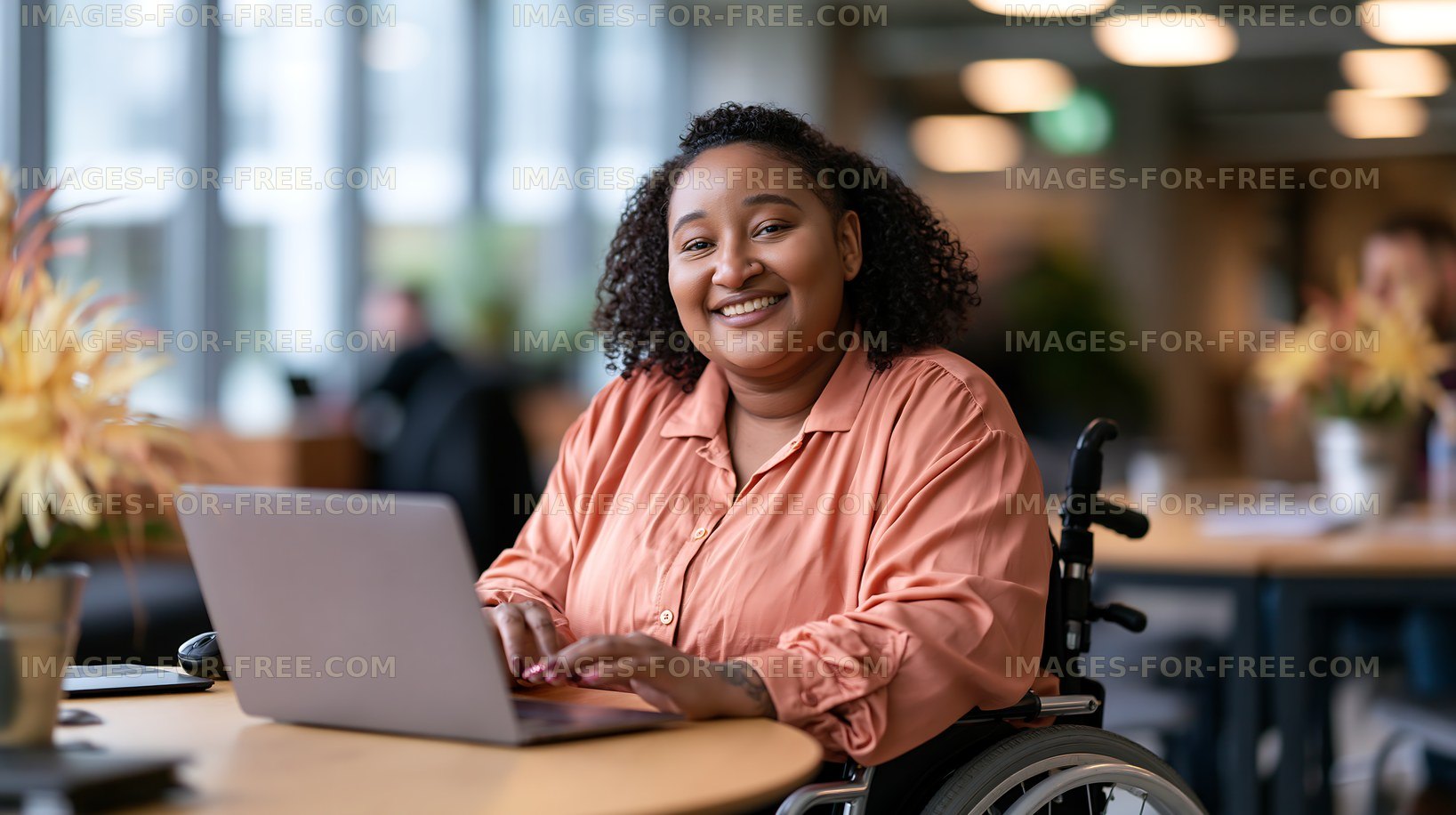 Woman in wheelchair working on laptop in modern office setting