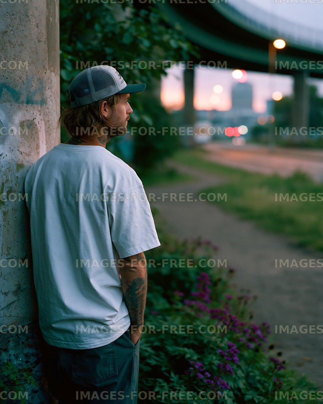 Man standing by a wall near a highway at dusk