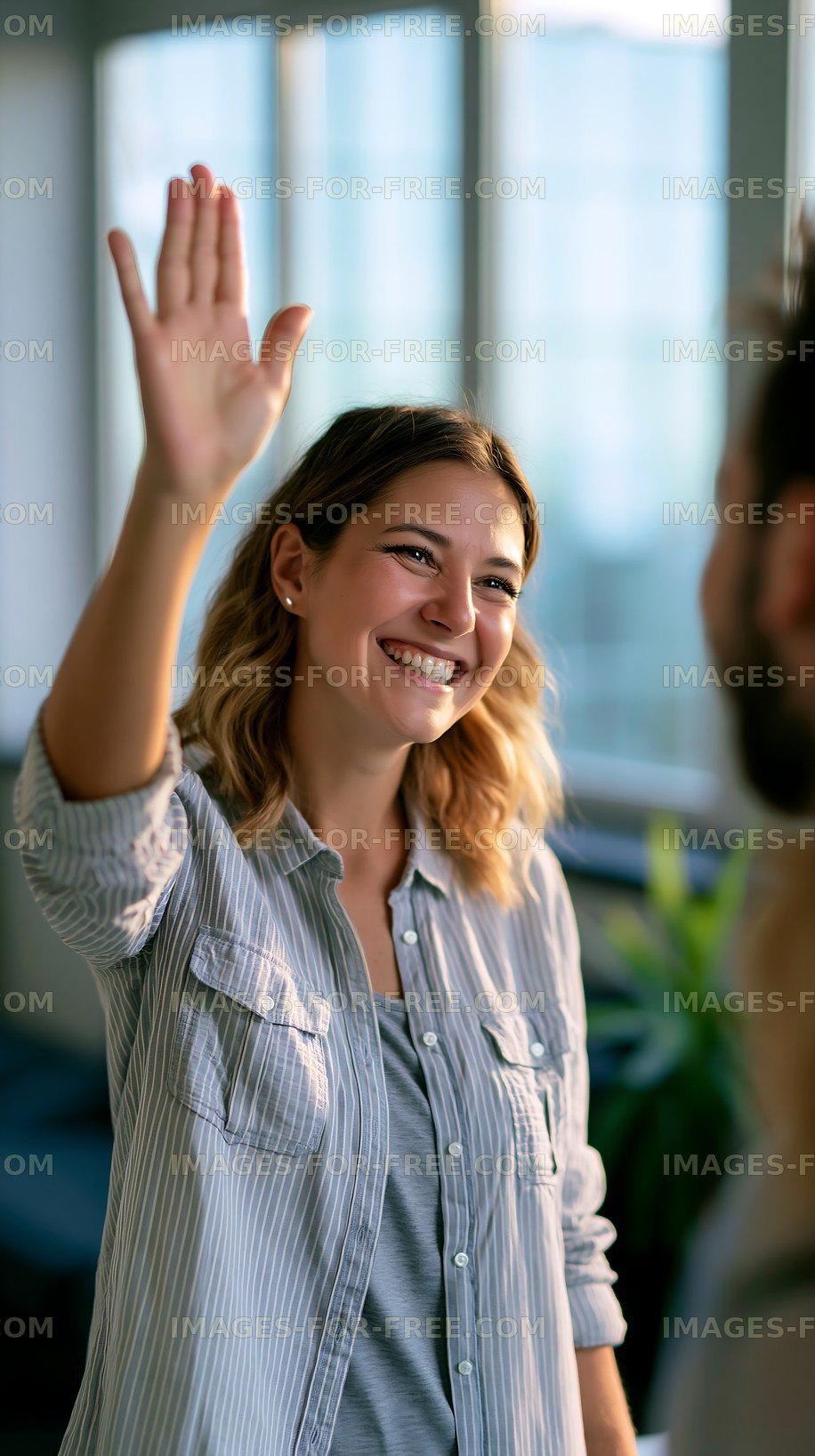 Person smiling and waving in an office setting during daylight