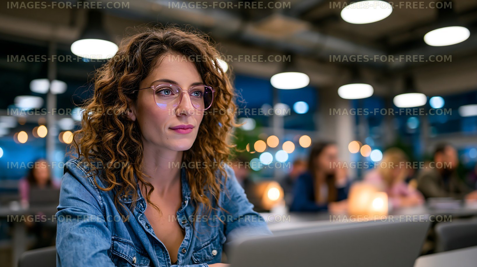 Woman working on laptop in a busy cafe at night