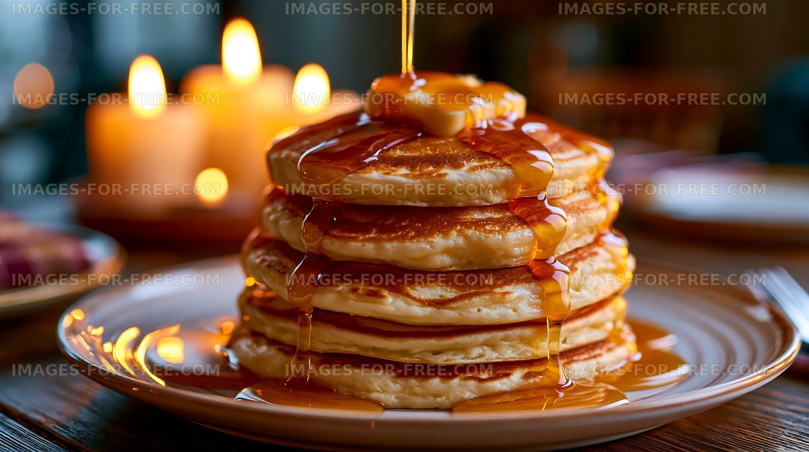 Pancake stack with syrup and butter in warm candlelight