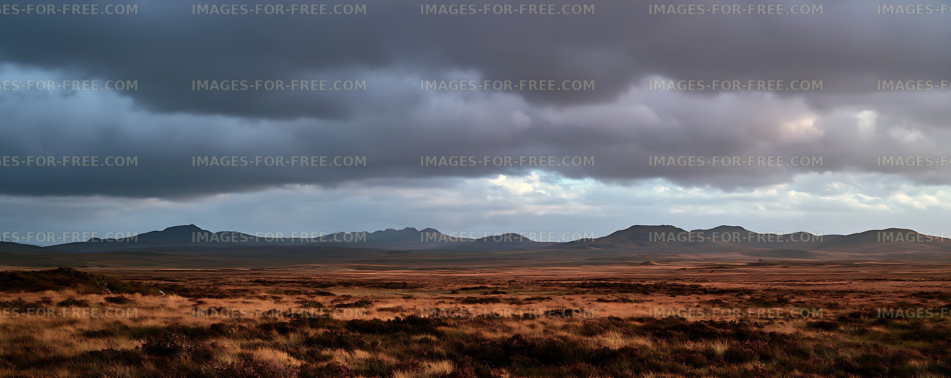 Panoramic grassland and mountains under storm clouds