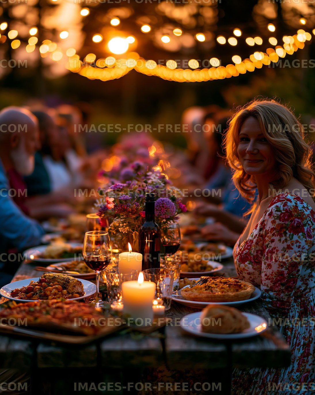 Warm outdoor dinner gathering with candlelight and string lights