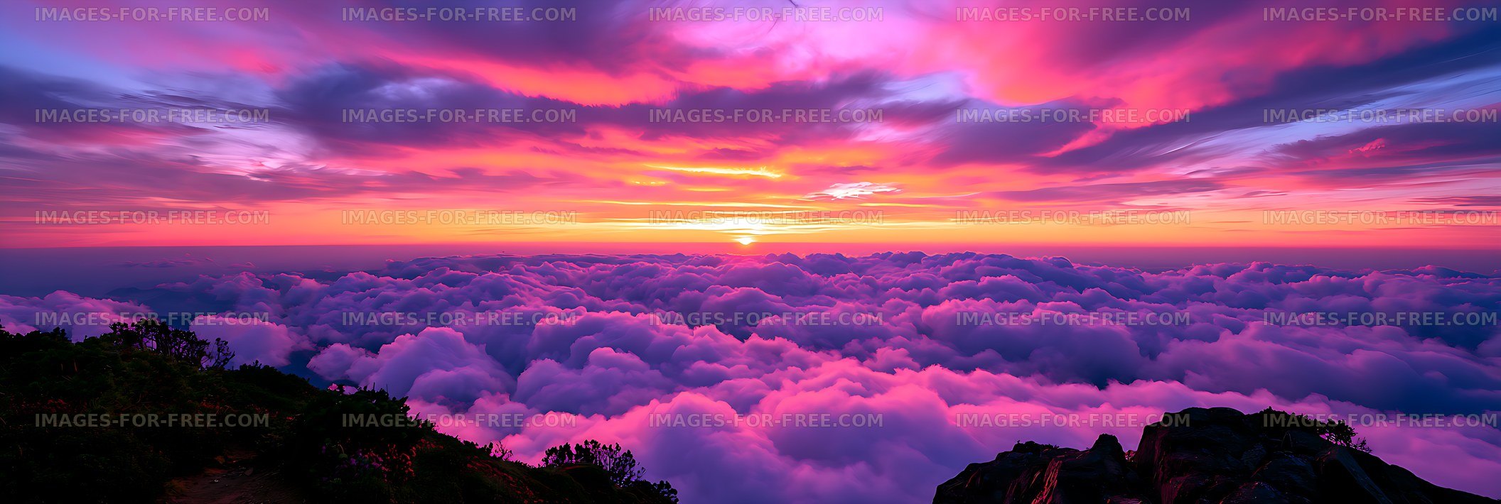 Colorful sunset over clouds and rugged mountain foreground
