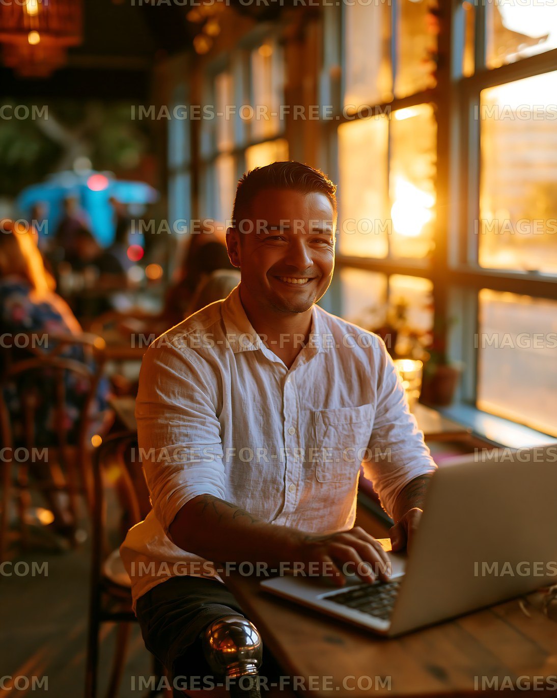 Smiling man working on a laptop beside cafe windows