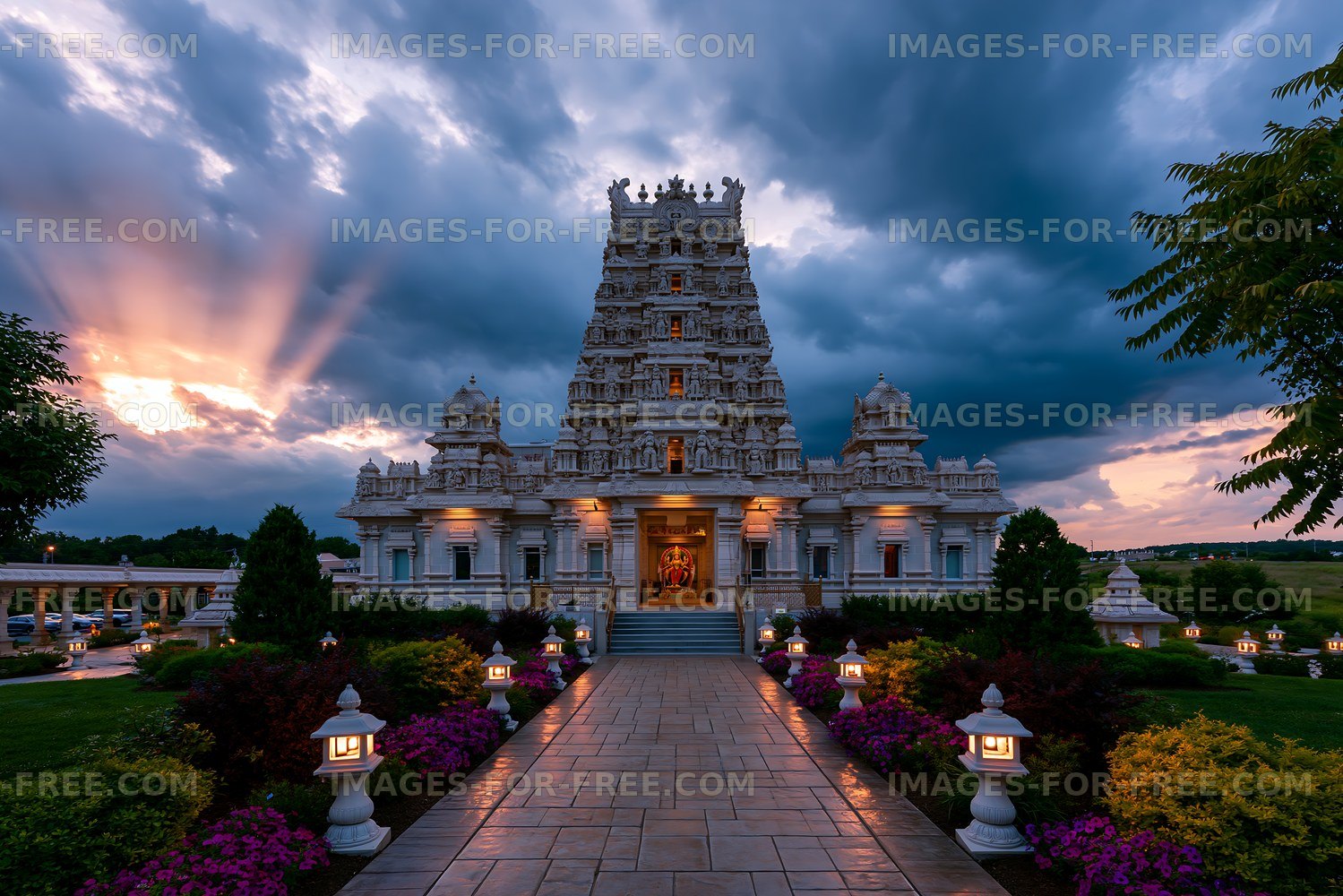 Illuminated Hindu temple and garden at dramatic sunset