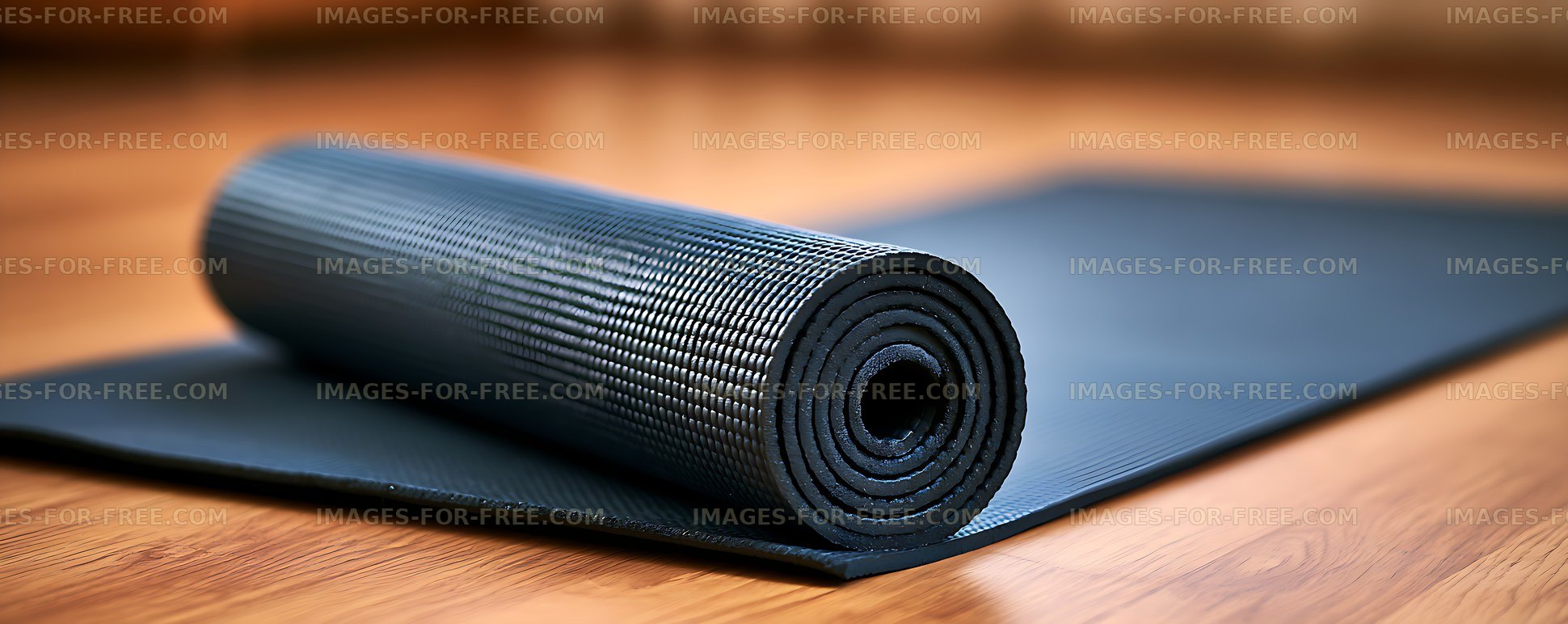 Black rolled exercise mat on wooden flooring