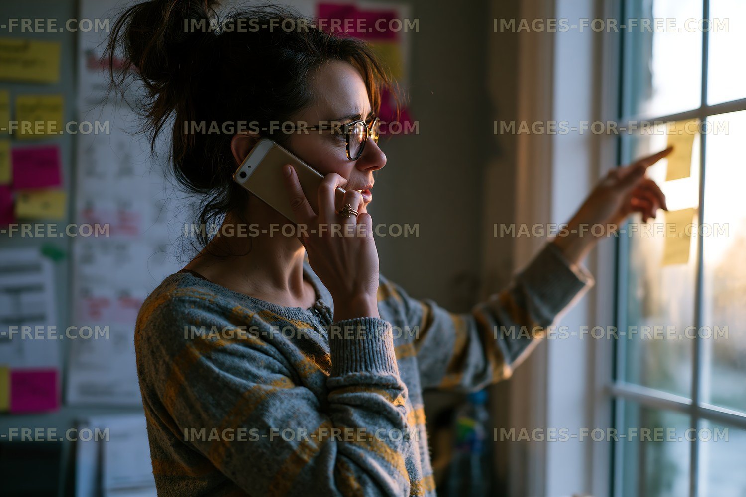Woman on phone pointing at window with sticky notes in background