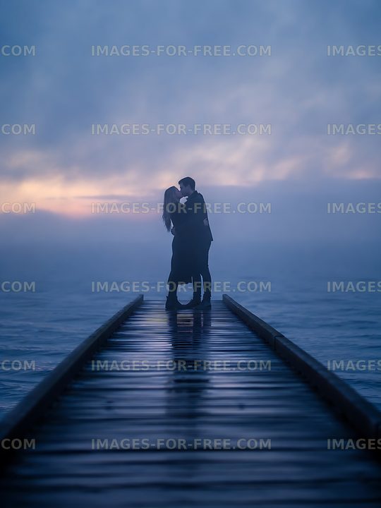 Couple kissing on wooden pier during foggy sunset