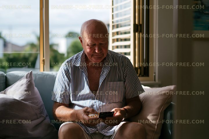 Man sitting on couch using smartphone indoors