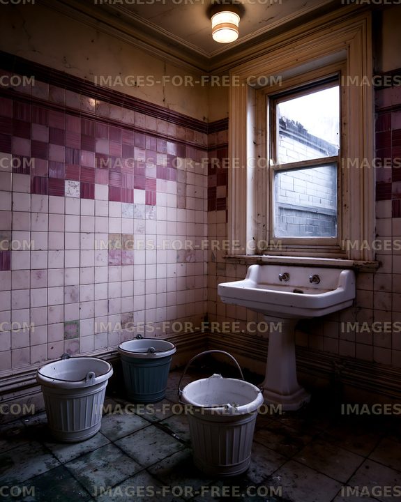 Old bathroom with dirty tiles and buckets on the floor
