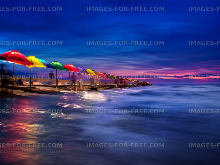Colorful umbrellas along a pier at sunset